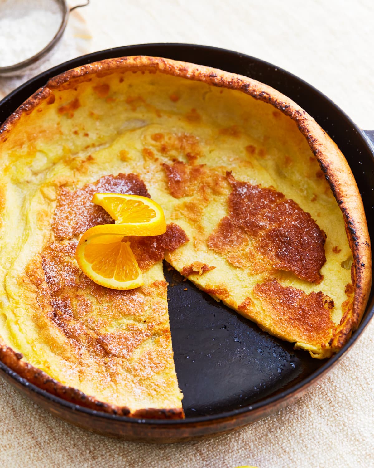 a gluten-free dutch baby in a pan missing a slice.
