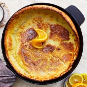 overhead view of a gluten-free dutch baby in a pan with an orange slice.