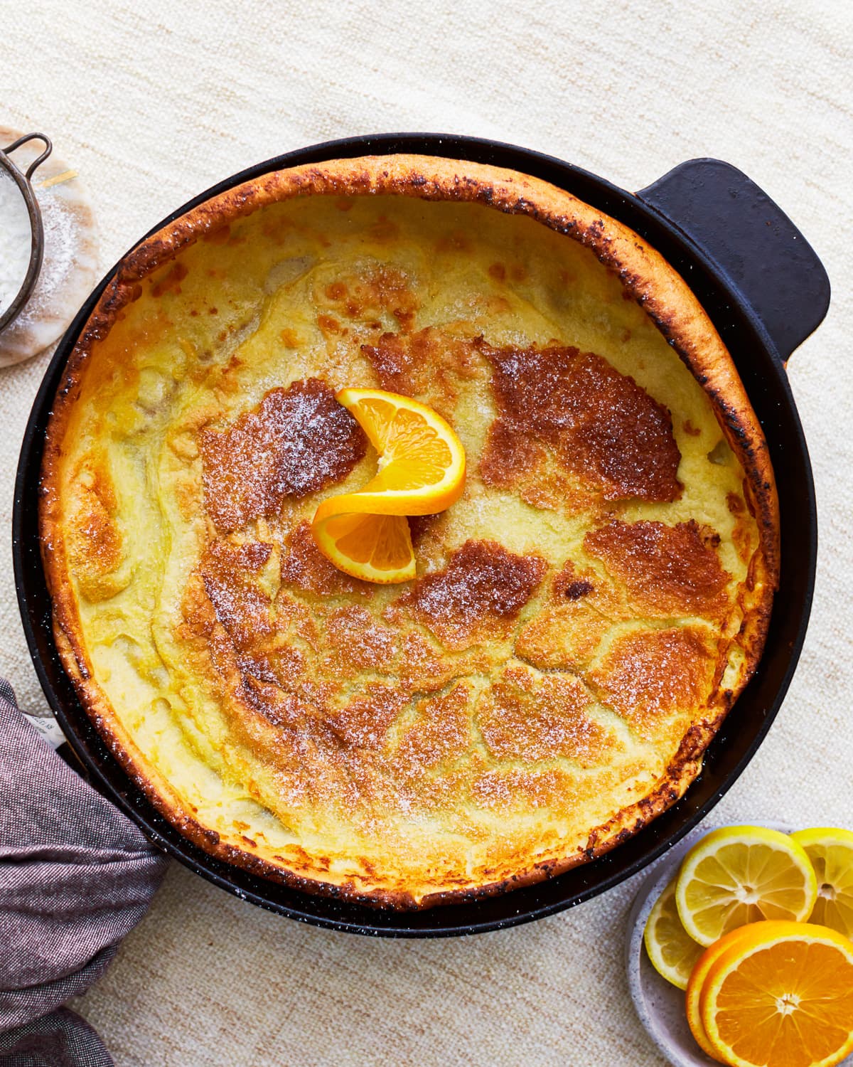 overhead view of a gluten-free dutch baby in a pan with an orange slice.