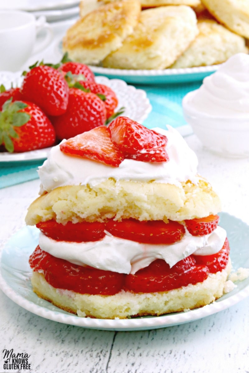 gluten-free strawberry shortcake on a blue plate with strawberries and shortcakes in the background