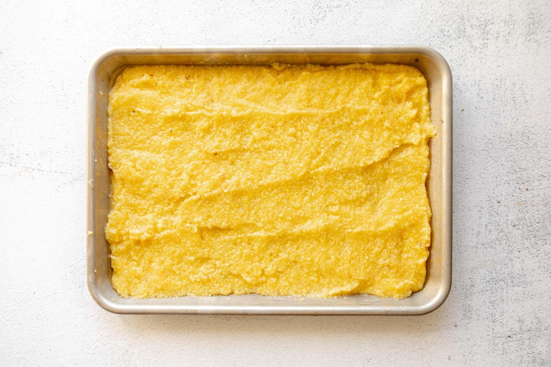 Grits spread out on a baking sheet.