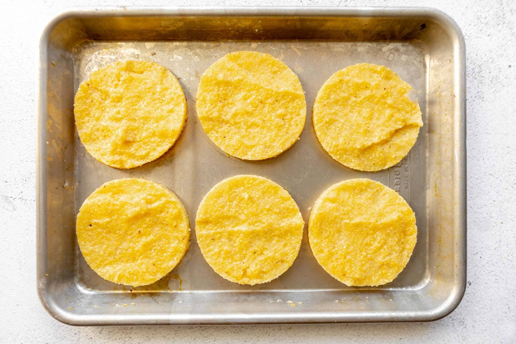 Grits cut into circles on a baking sheet.