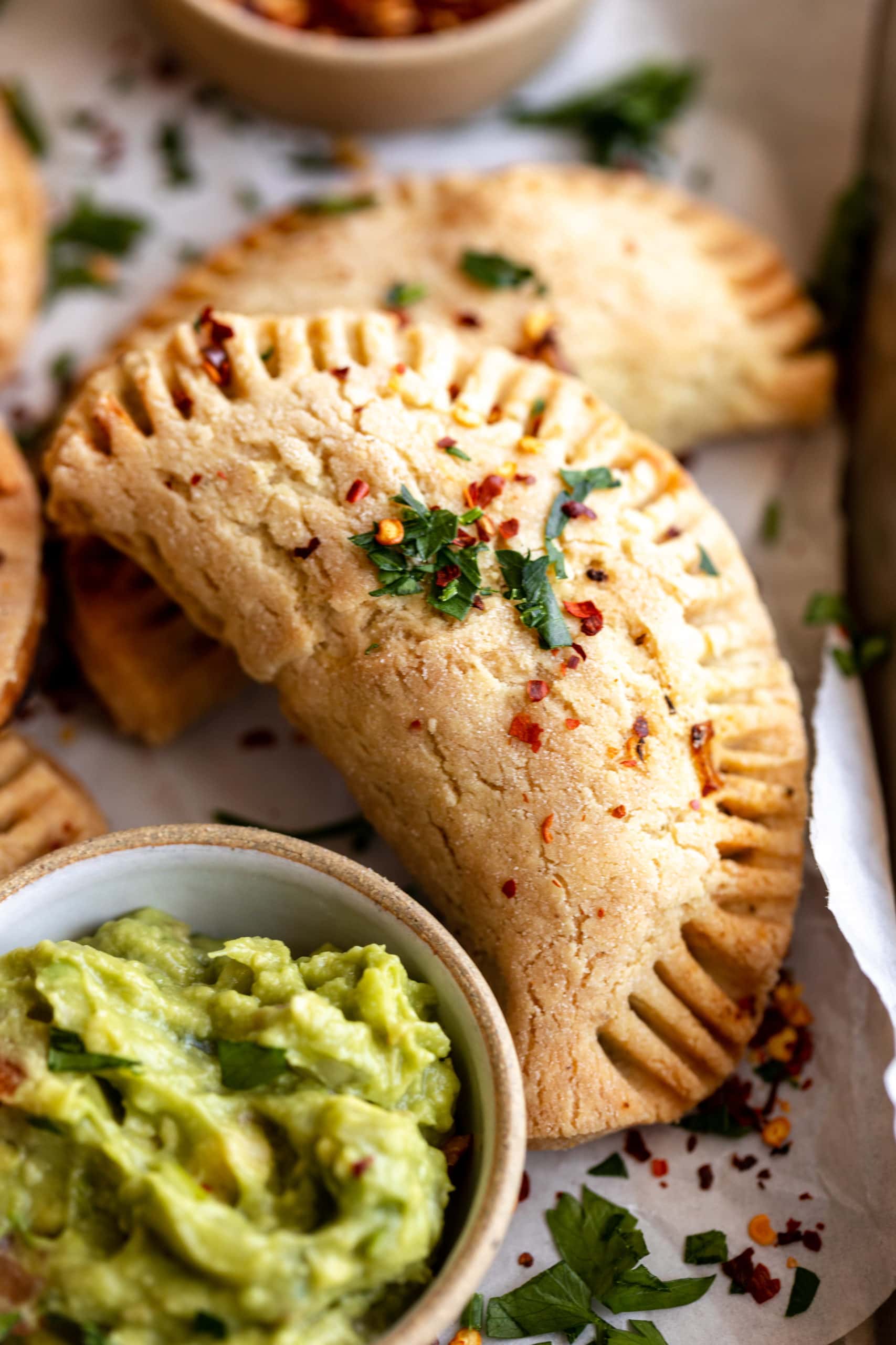 a gluten-free empanada next to a bowl of guacamole.