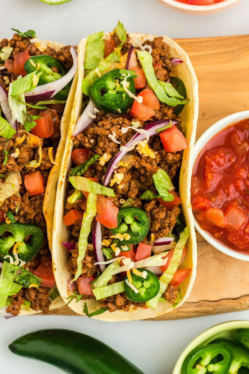 close up view of gluten-free tacos on a wooden cutting board.