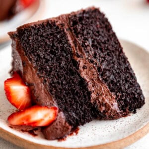a slice of almond flour chocolate cake on a white plate with strawberries.