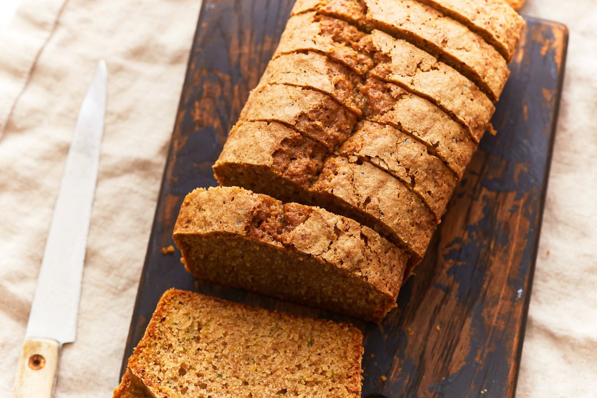 gluten-free zucchini bread sliced on a wood cutting board with a knife