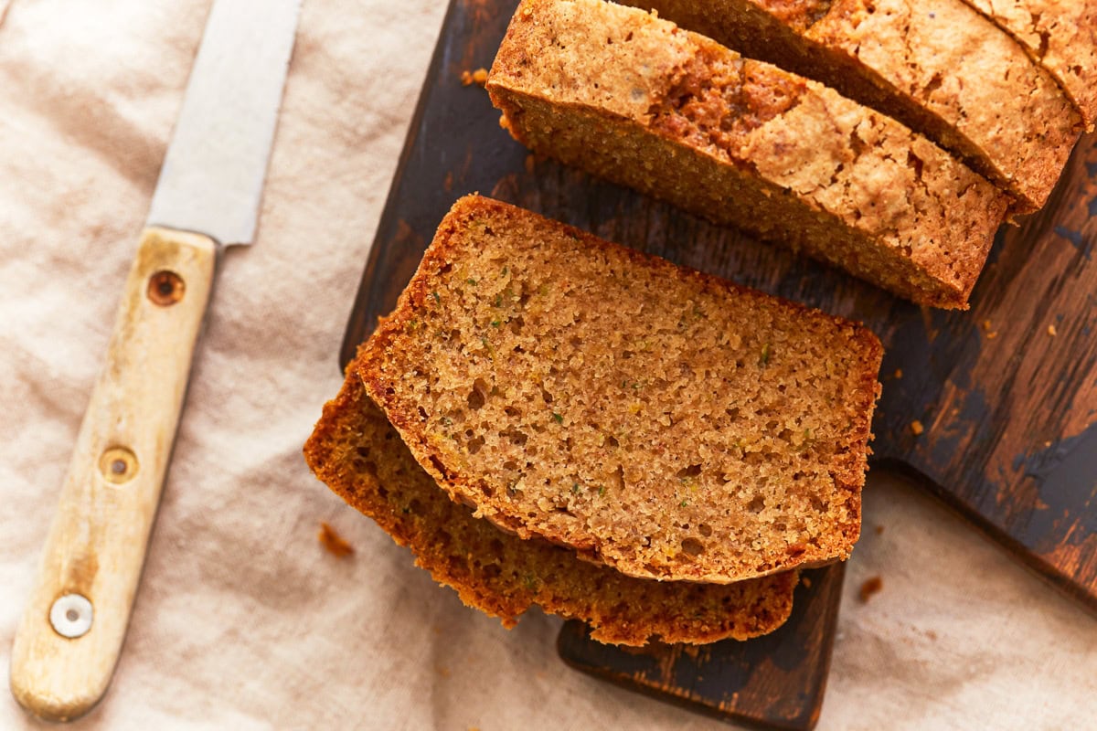 gluten-free zucchini bread sliced on a wood cutting board with a knife