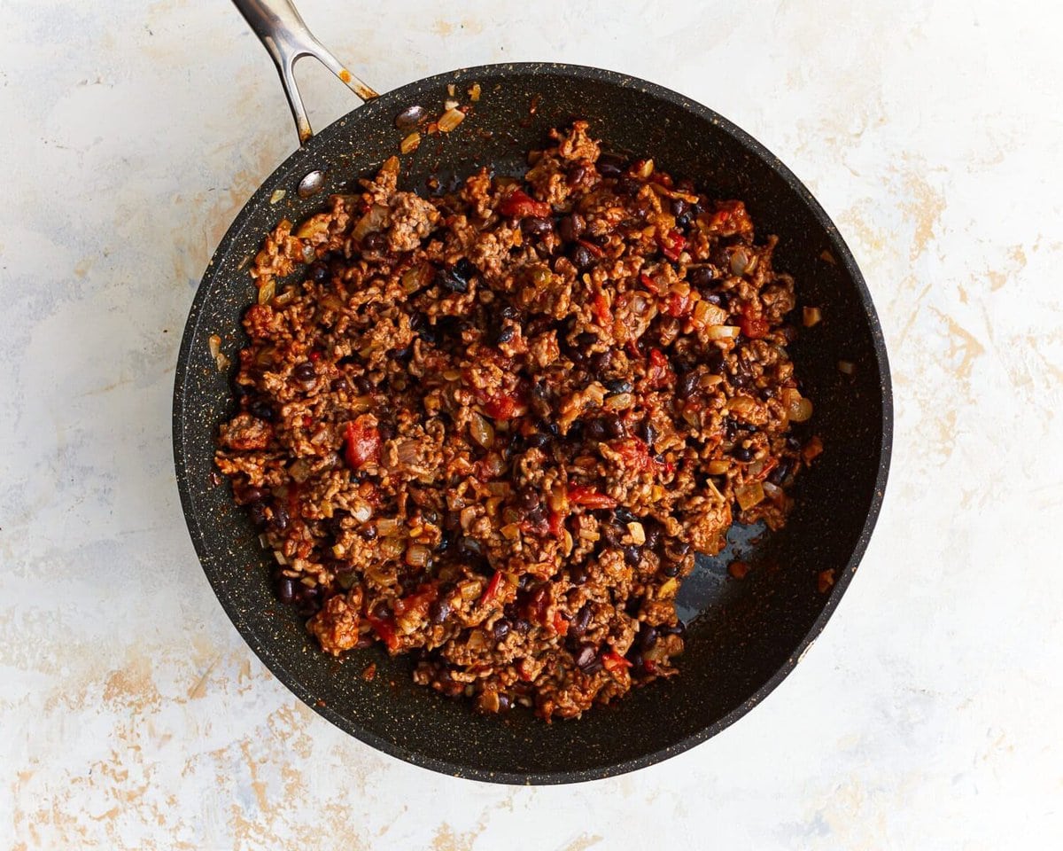 Cooked ground beef and salsa in a skillet.