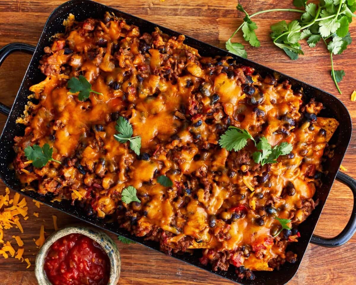 Baked walking taco topped with cilantro with a side of salsa.