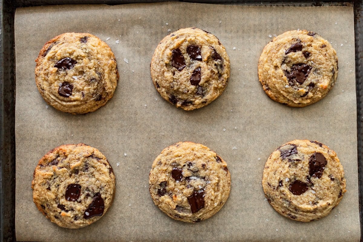 coconut flour chocolate chip cookies on a parchment lined baking sheet topped with flaky salt