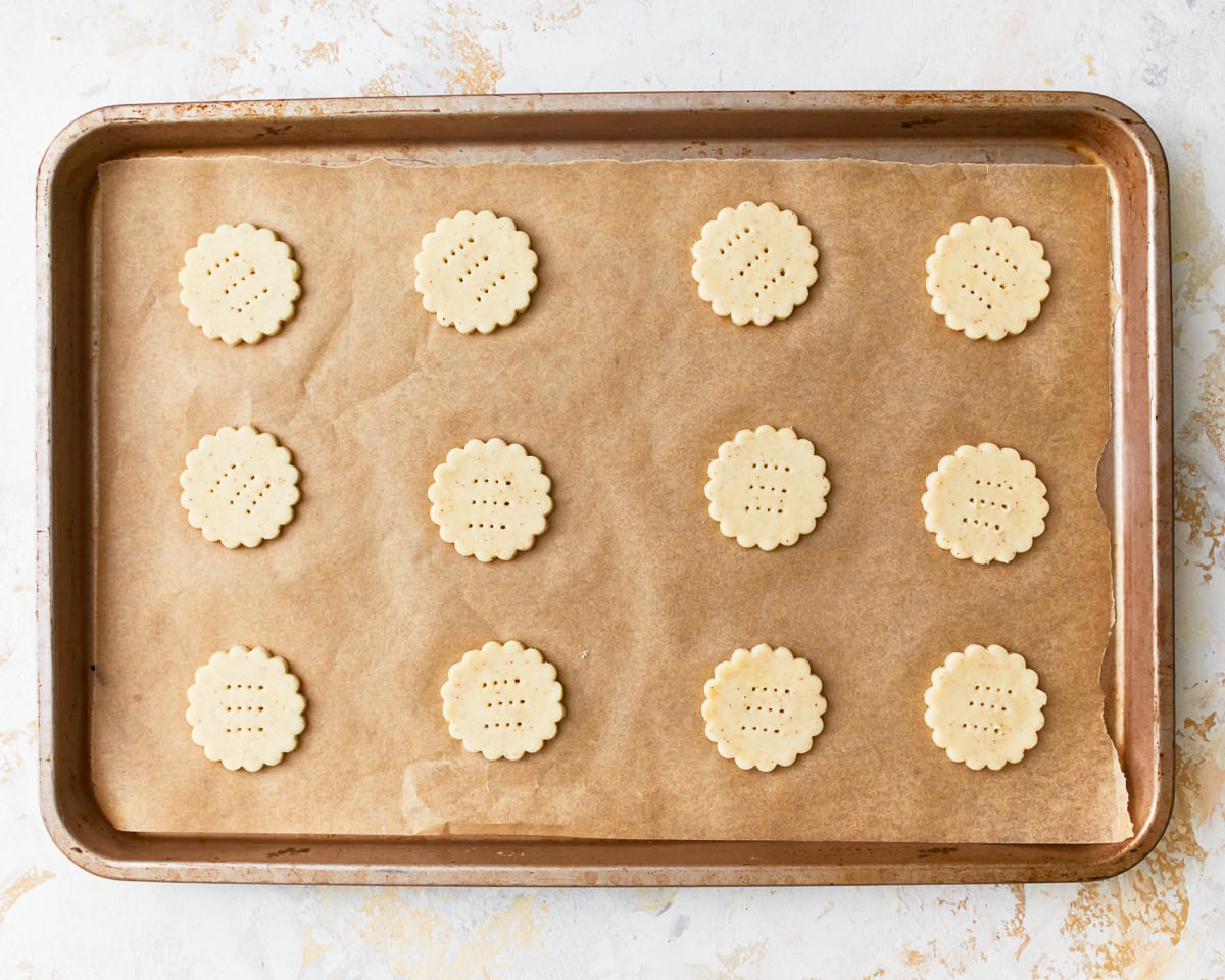 Unbaked gluten-free ritz crackers on a parchment lined baking sheet,