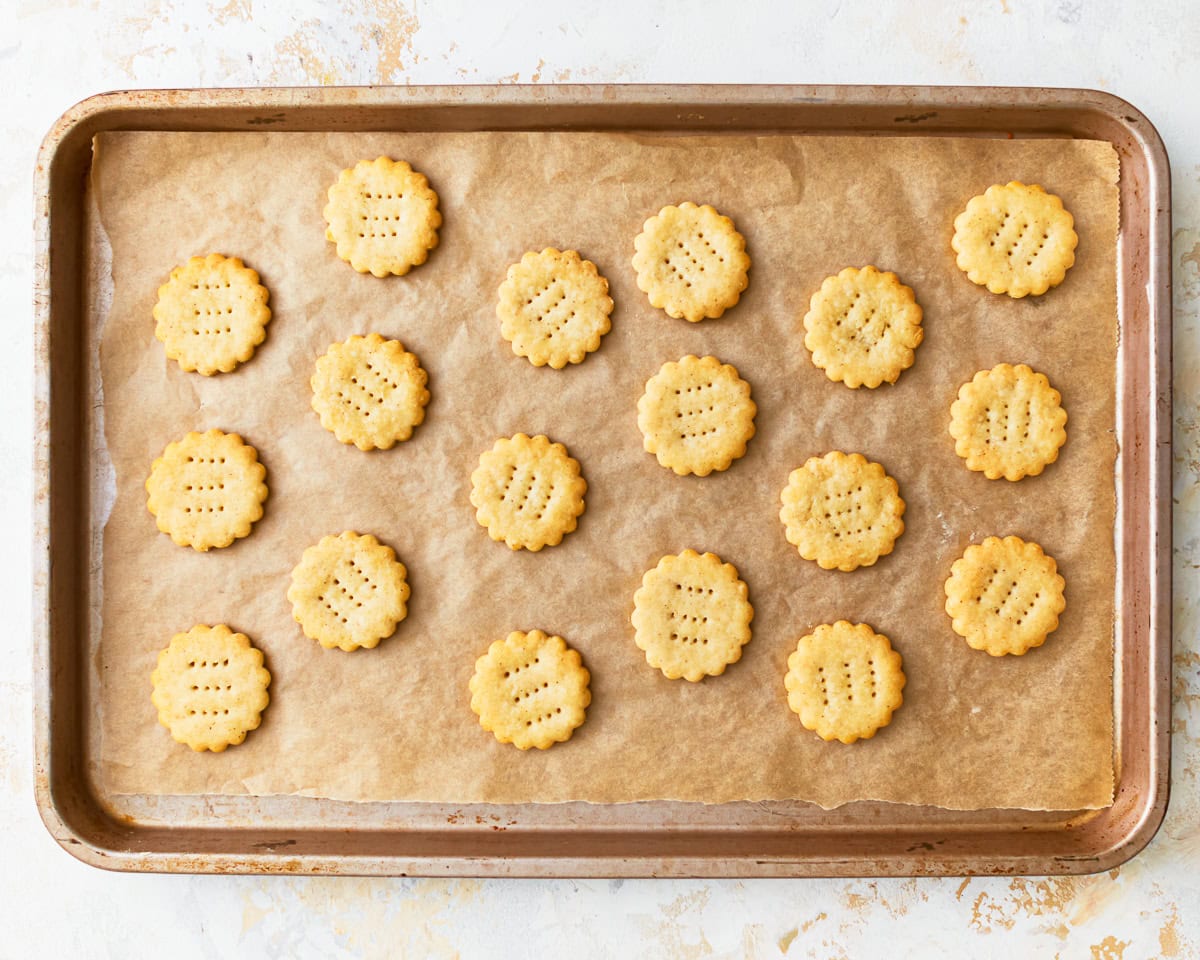 Freshly baked homemade gluten-free ritz crackers on a parchment lined baking sheet.