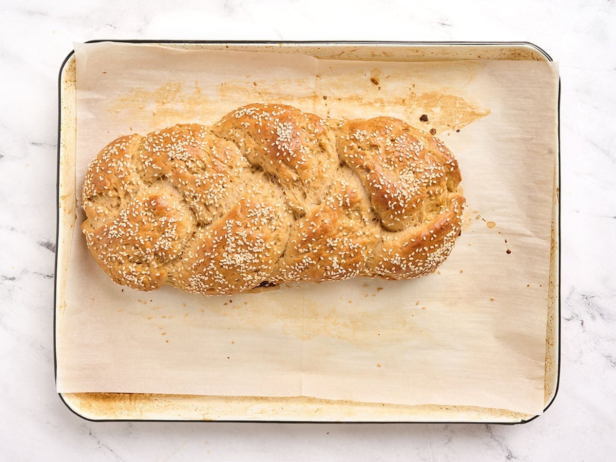 Freshly baked gluten free challah bread loaf on a parchment lined baking sheet.