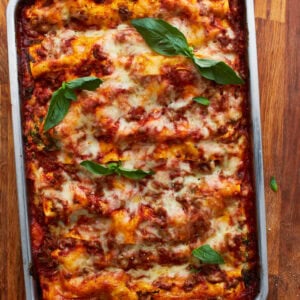 a whole cooked gluten-free lasagna in a tin baking dish topped with basil.