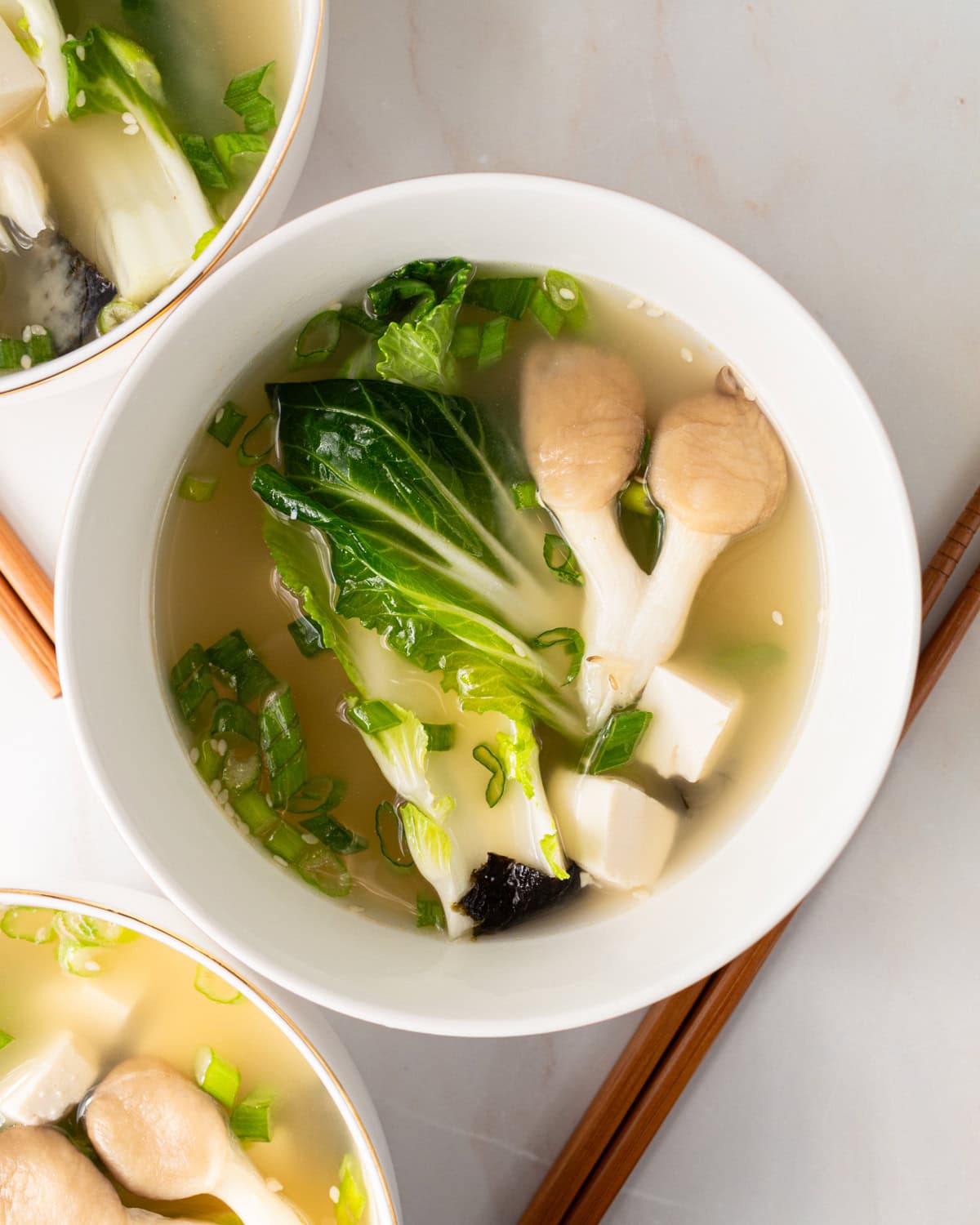 gluten-free miso soup in a white bowl with bok choy and mushrooms and chopsticks next to the bowl