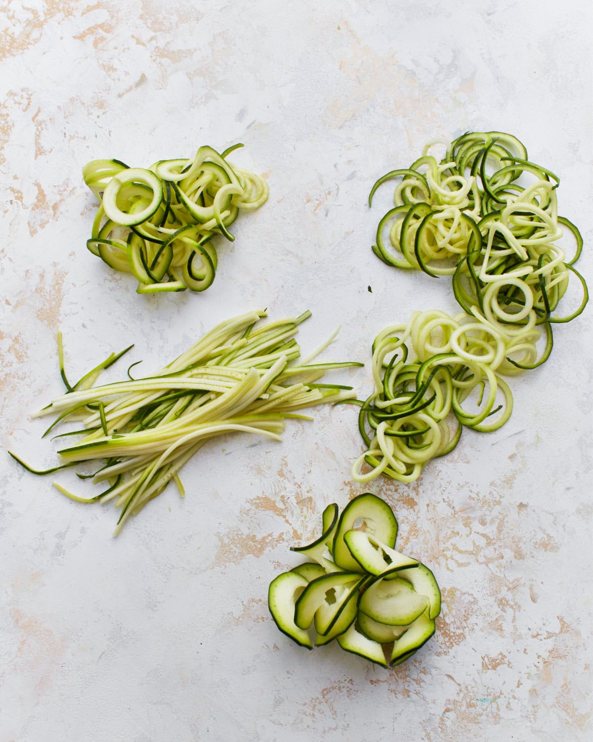 spiralized zucchini noodles, juliened zucchini noodles, and shaved zucchini noodles in piles