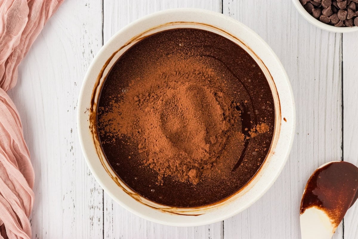 melted chocolate mixture in white bowl with cocoa powder on top 