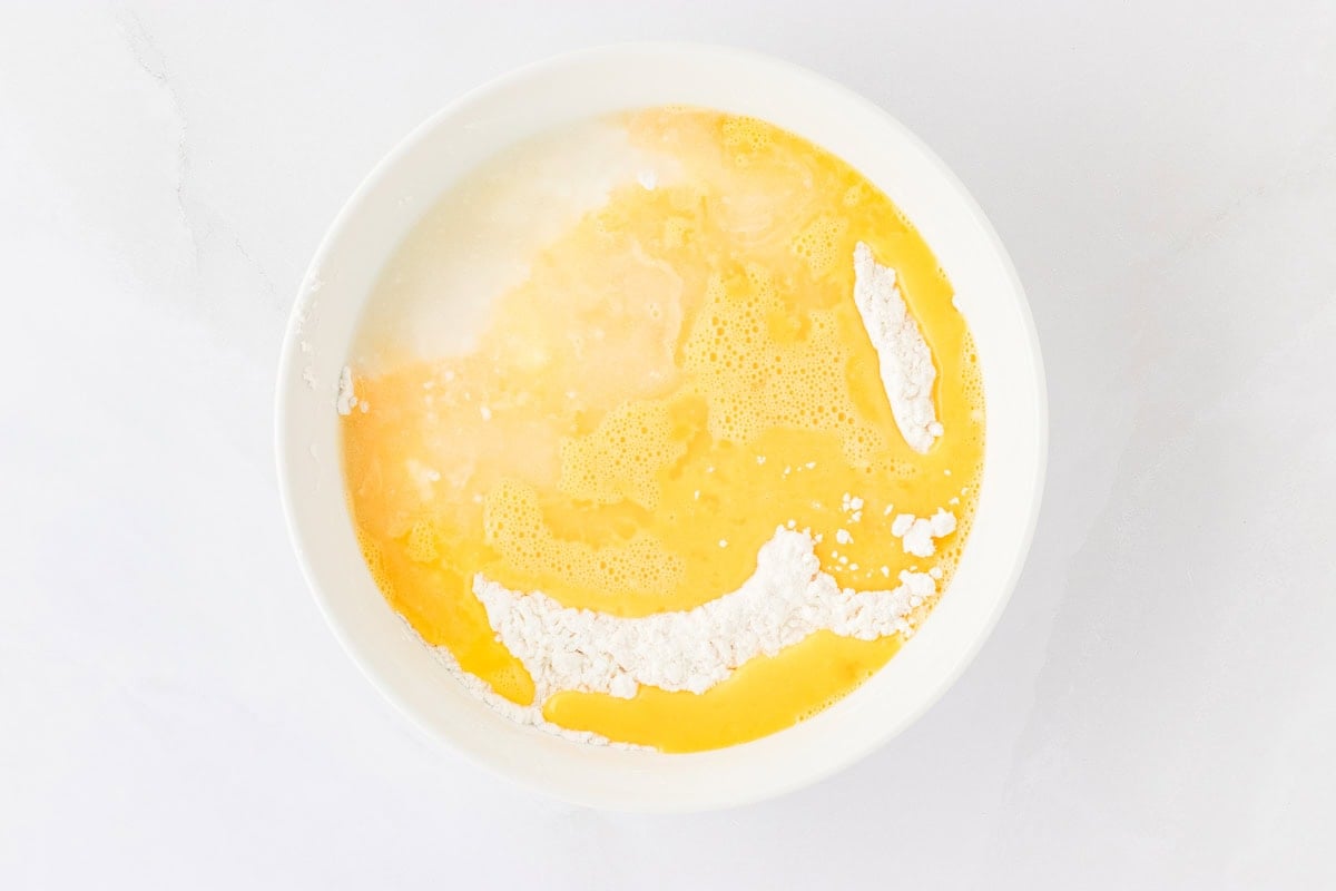 gluten-free flour mixture with whisked eggs on top in white bowl