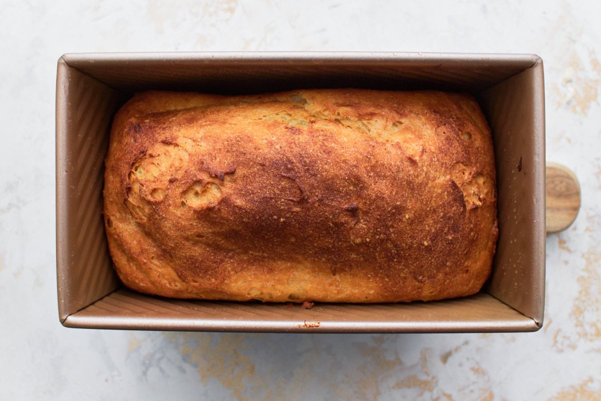 baked, golden brown gluten-free bread loaf in loaf pan on white counter top