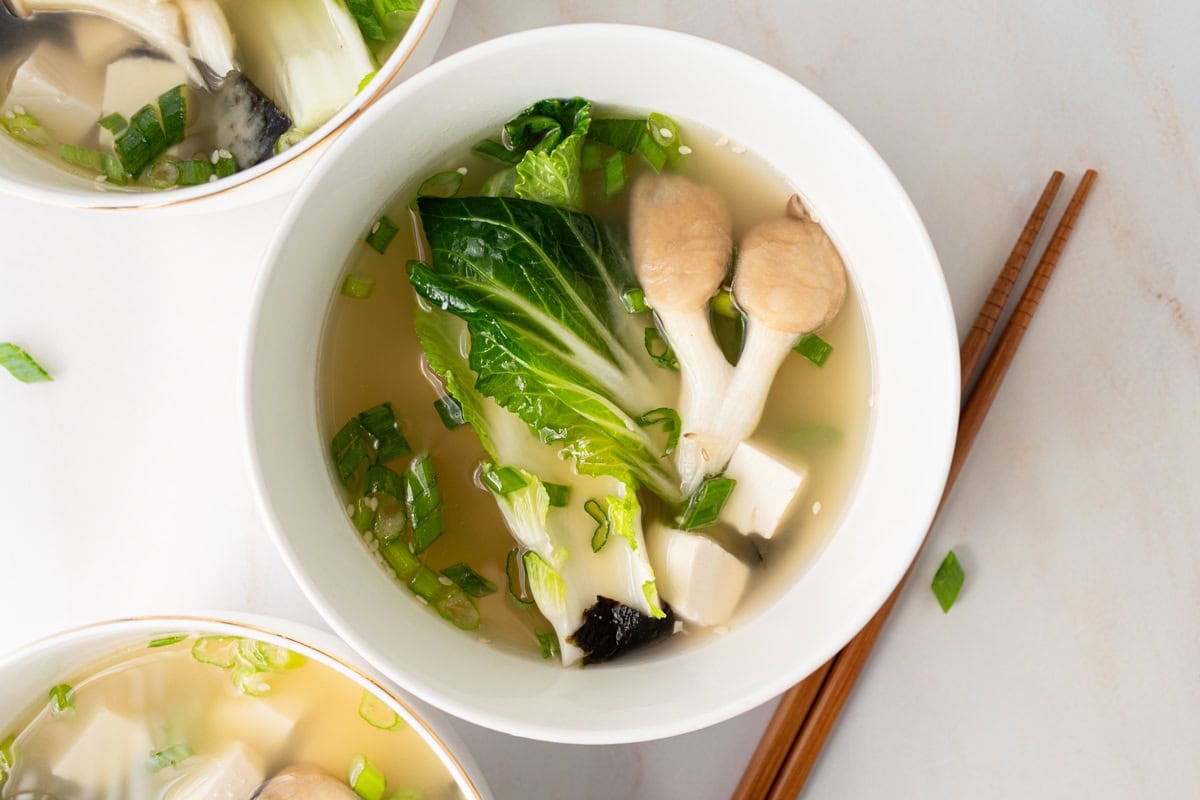 horizontal shot of gluten-free miso soup in white bowl with chopsticks next to it