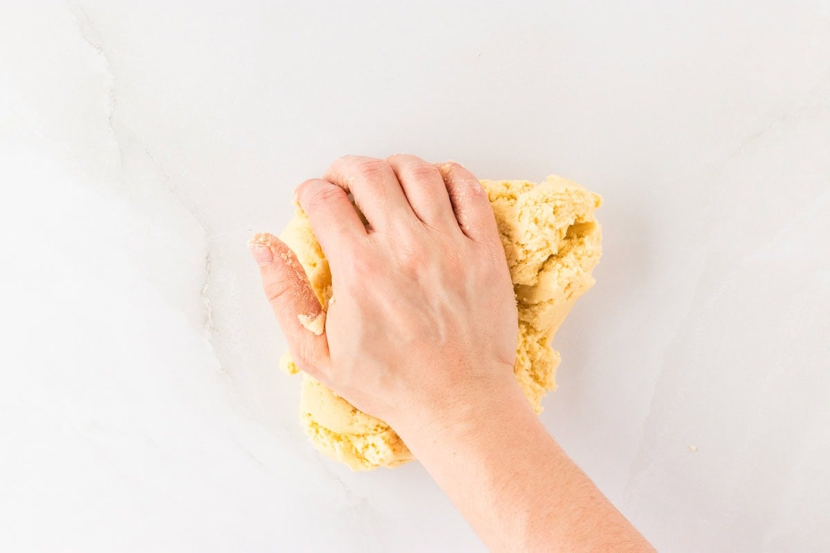 hand kneading gluten-free egg roll dough on white surface