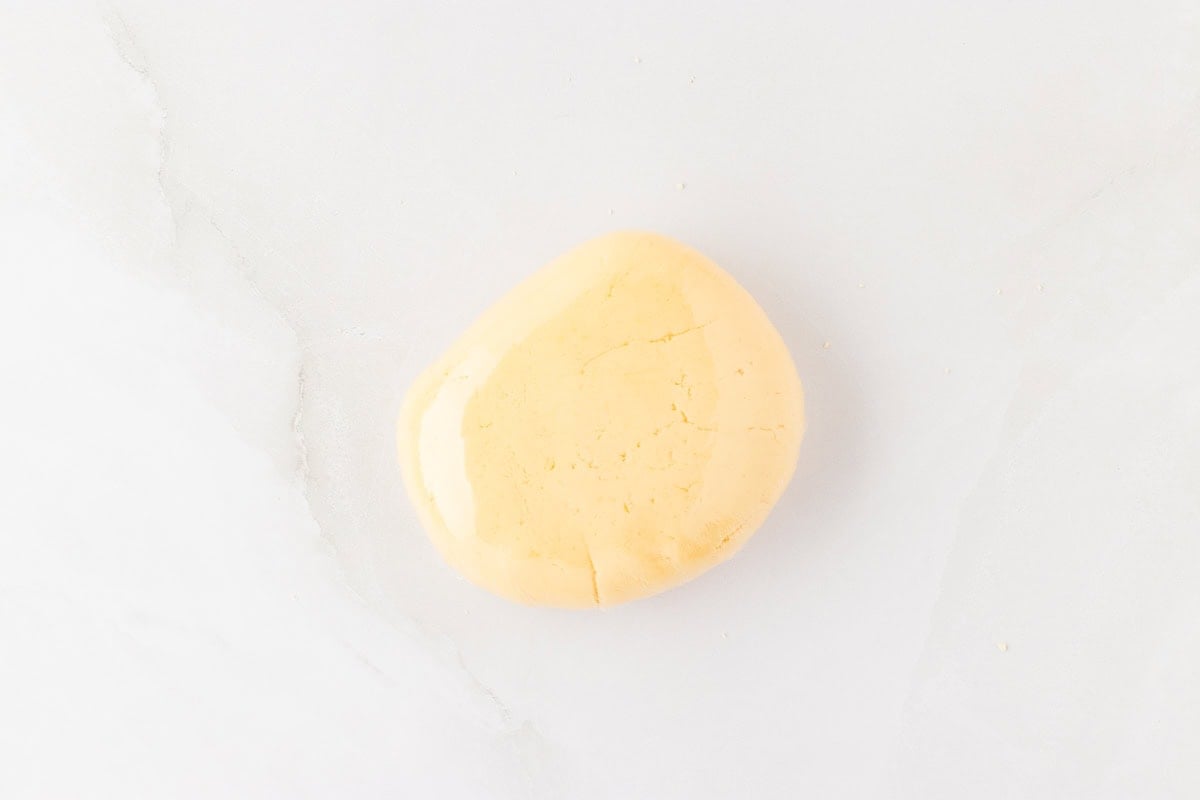 smooth ball of gluten-free egg roll dough on white surface