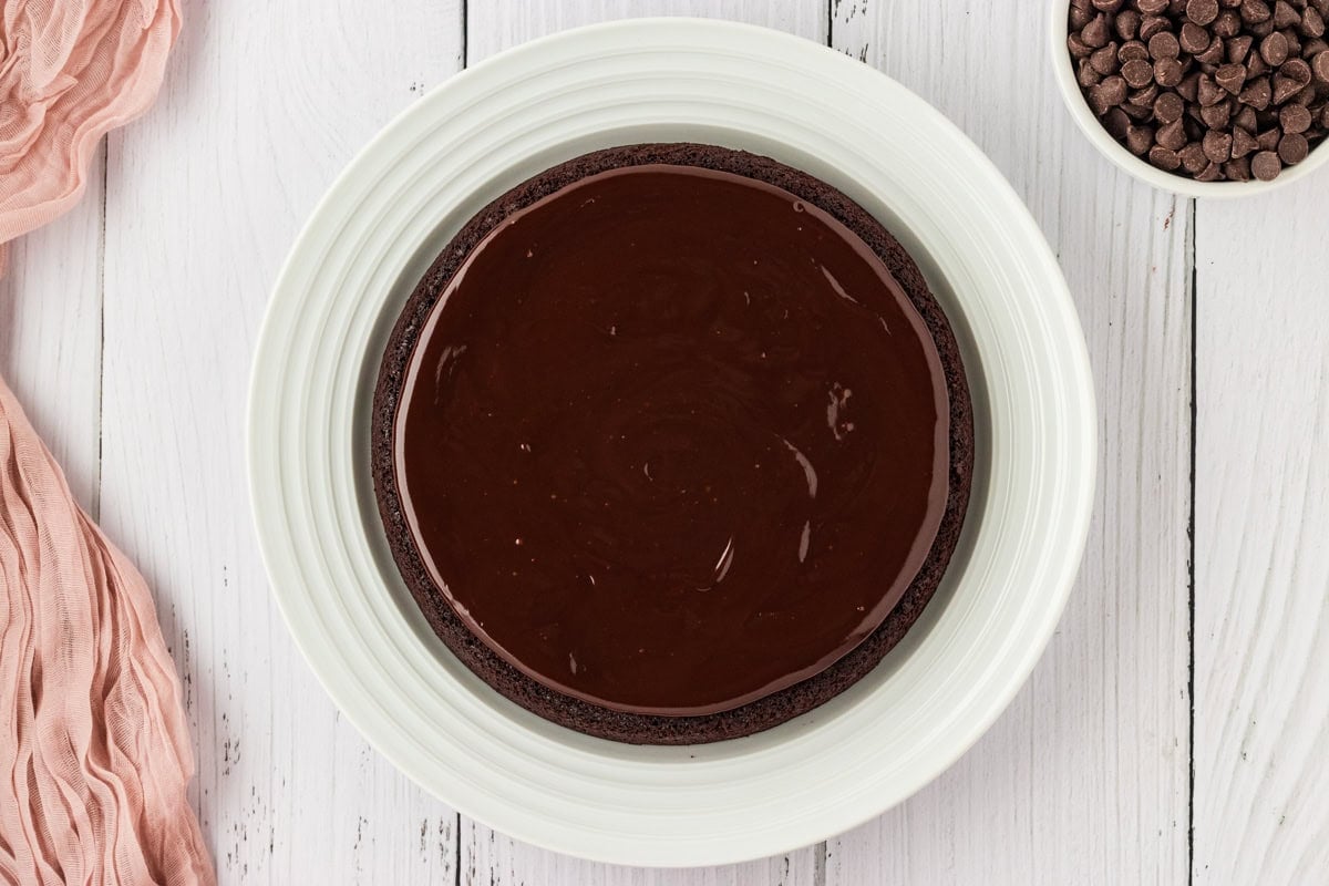 chocolate ganache glazed flourless chocolate cake on a white platter