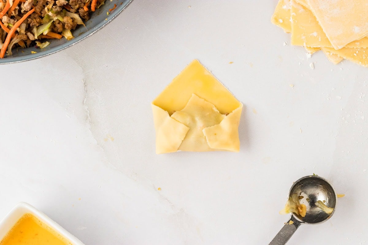 short corners of gluten-free egg roll dough square being folded in