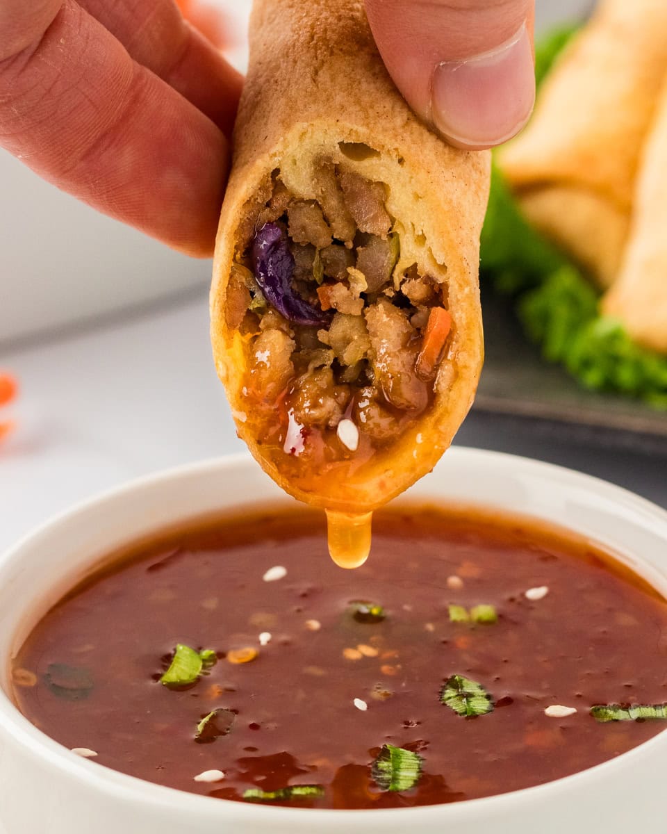 gluten-free egg roll being dipped in sweet chili sauce
