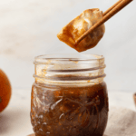dumpling being dipped into mason jar of orange reduction sauce with chopsticks