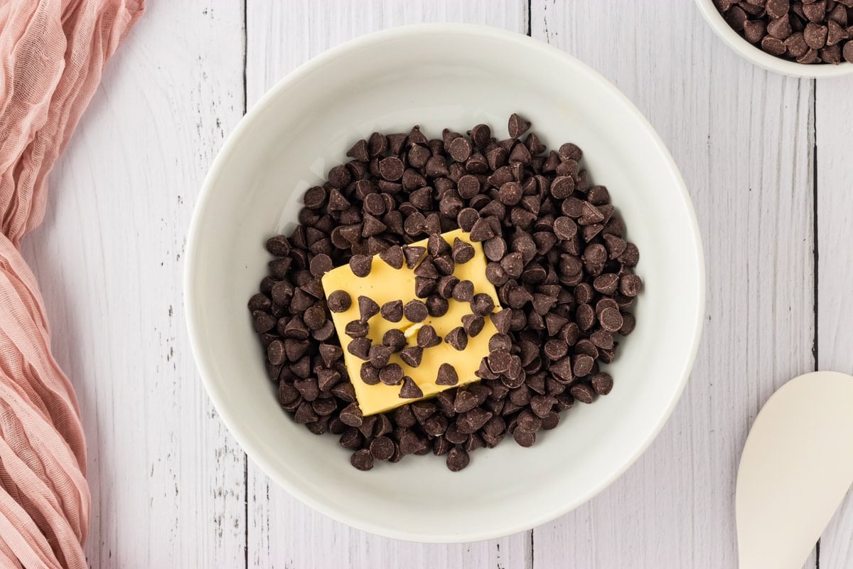 a white bowl filled with chocolate chips and a block of unsalted butter
