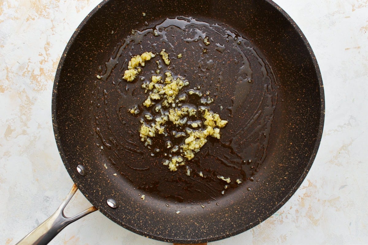 black skillet with sautéed minced garlic and oil