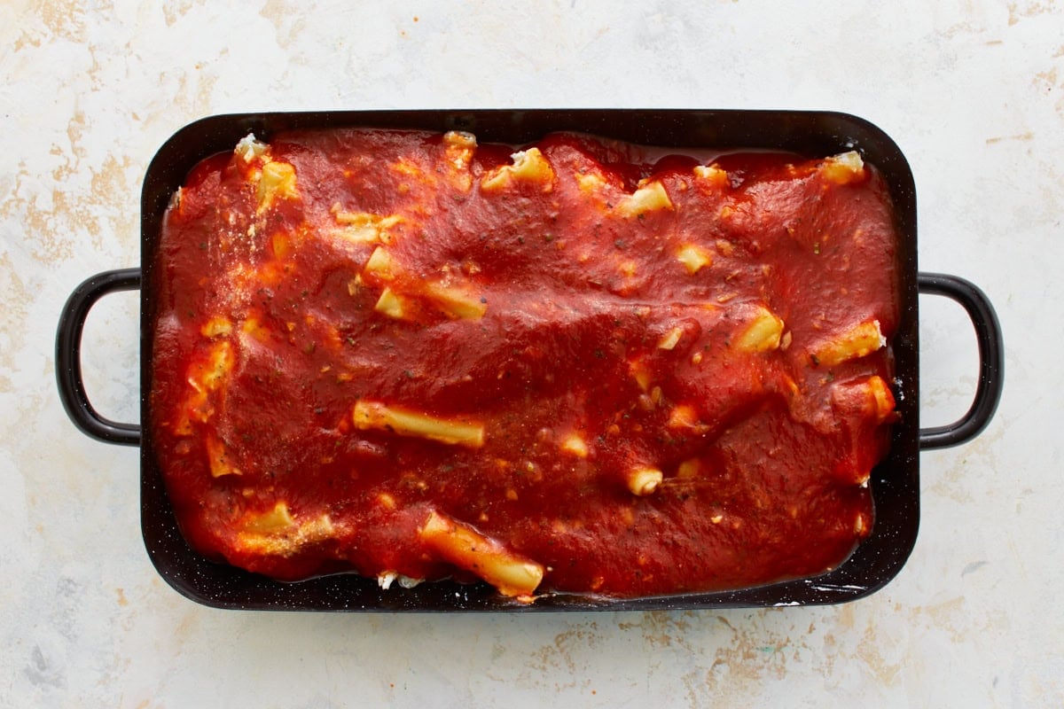 gluten-free ziti in black baking dish covered in marinara sauce