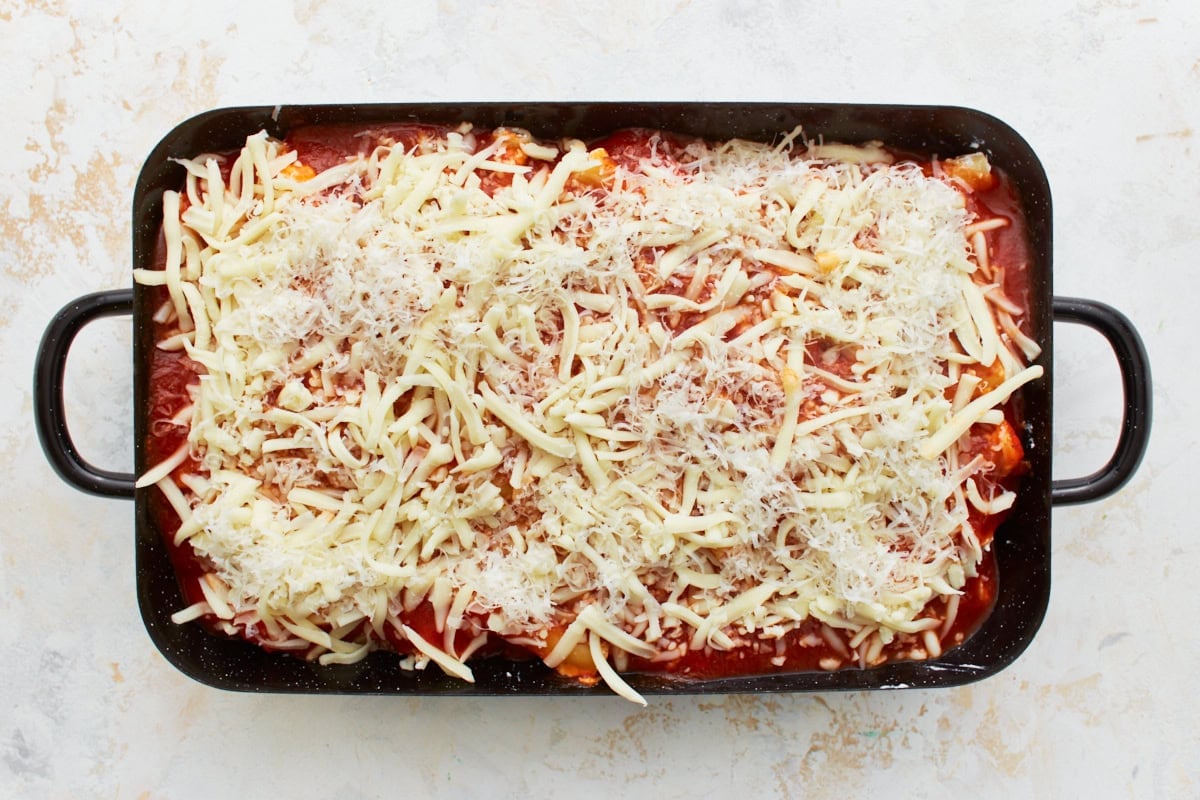 gluten-free ziti in a black baking dish, with marinara and sprinkled with parmesan and mozzarella cheese