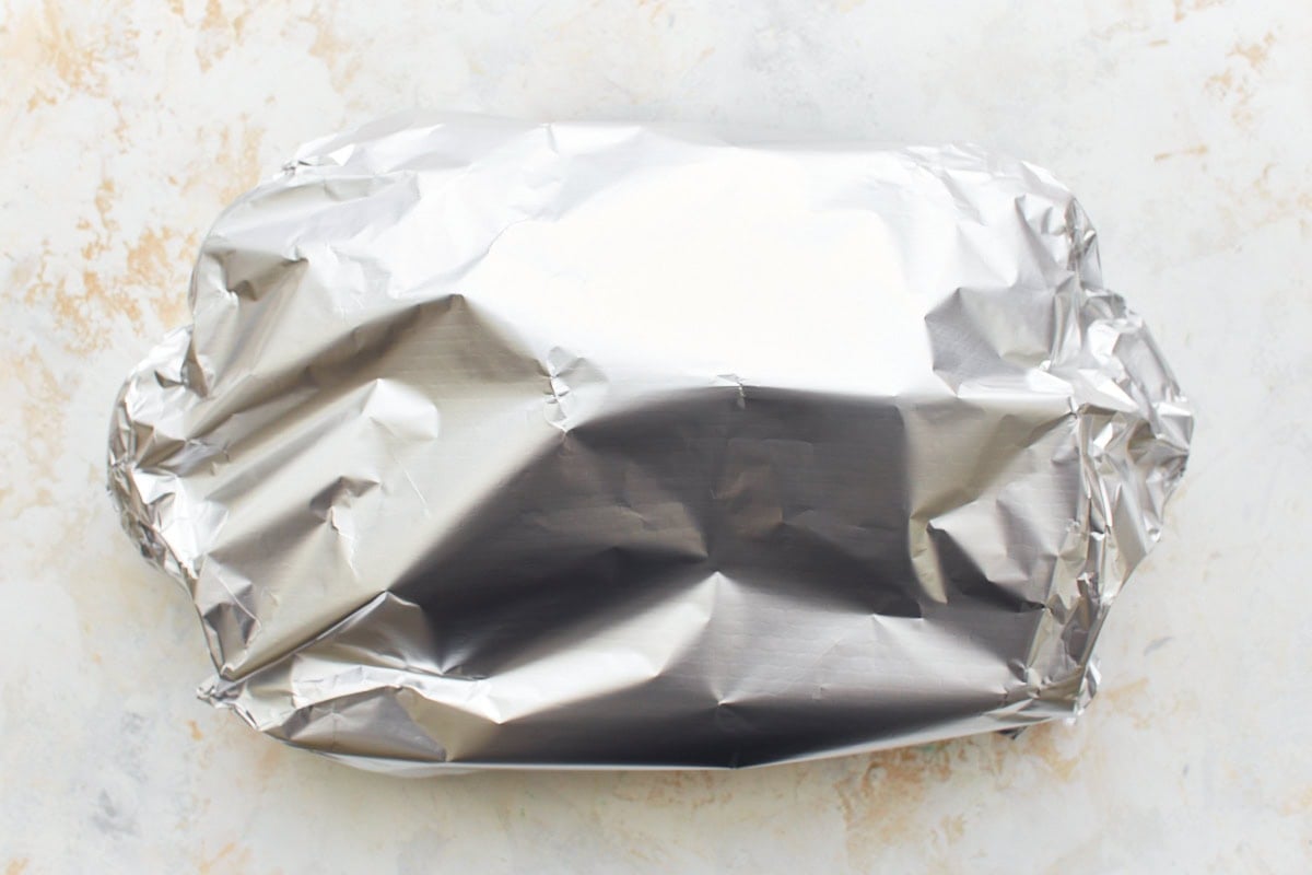 aluminum foil covering baked ziti in baking dish