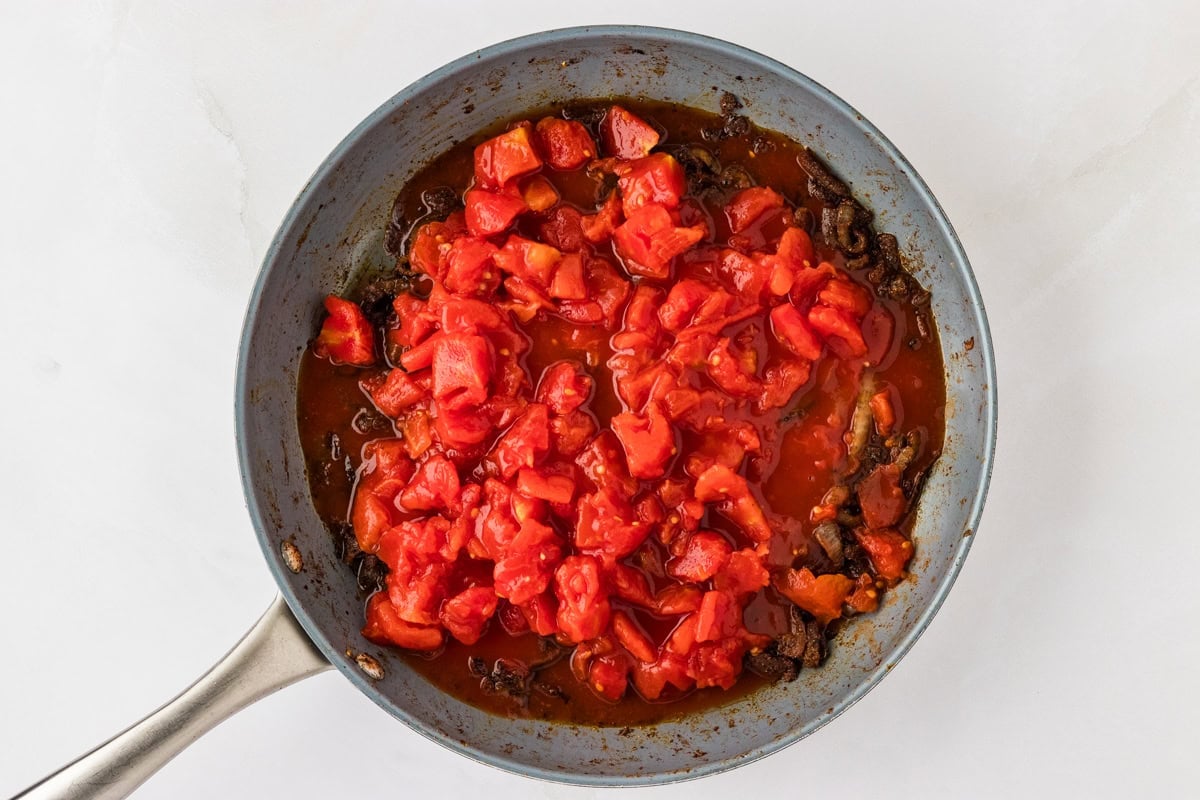 chopped tomatoes on top of sautéed onions and spices