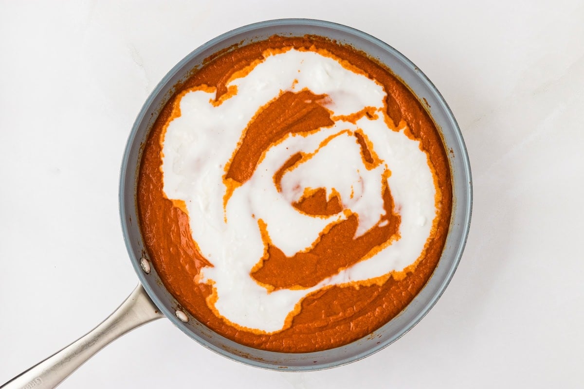 butter chicken sauce in skillet with coconut cream on top
