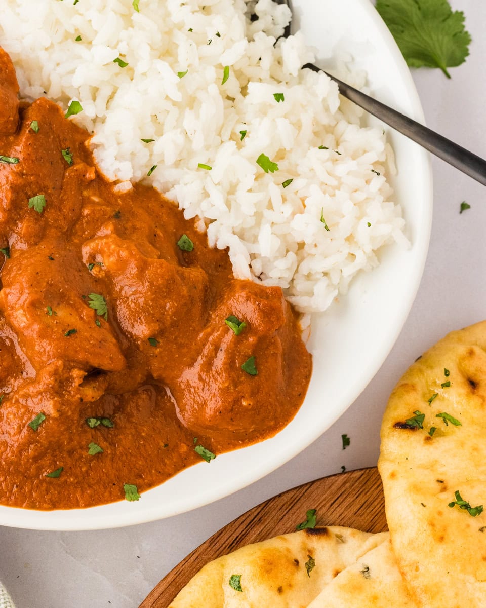 dairy free butter chicken in white bowl with basmati rice with naan on the side