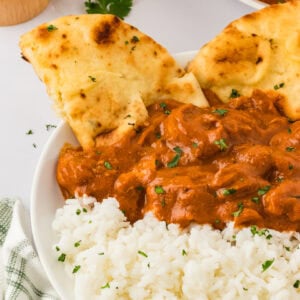 dairy free butter chicken over basmati rice in a white bowl with naan bread