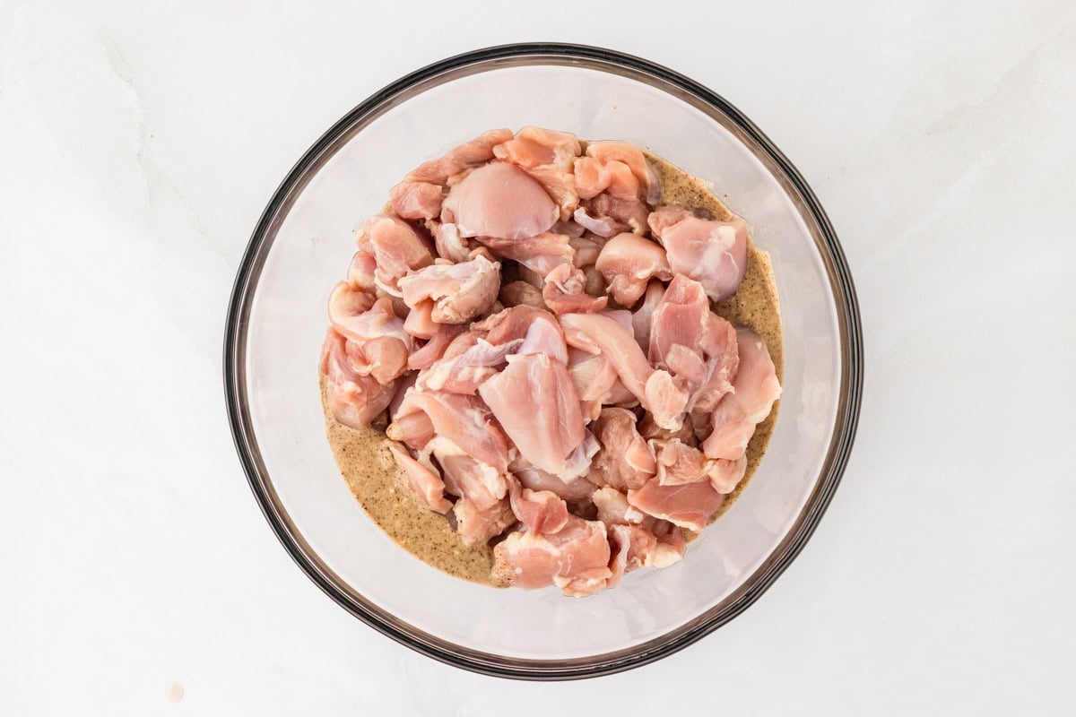 raw chicken in a coconut cream marinade in a glass bowl