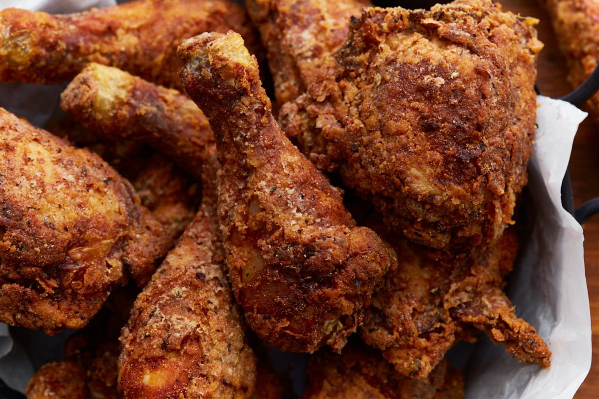Crispy golden brown gluten-free fried chicken stacked in a paper towel lined cast iron skillet