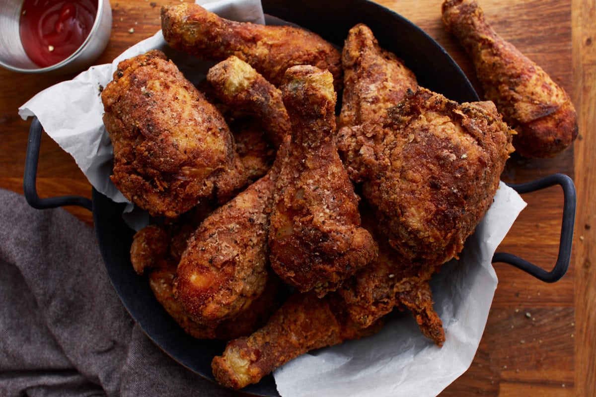 Cast iron skillet filled with gluten-free Southern-style fried chicken, featuring golden-brown, crispy drumsticks and thighs.