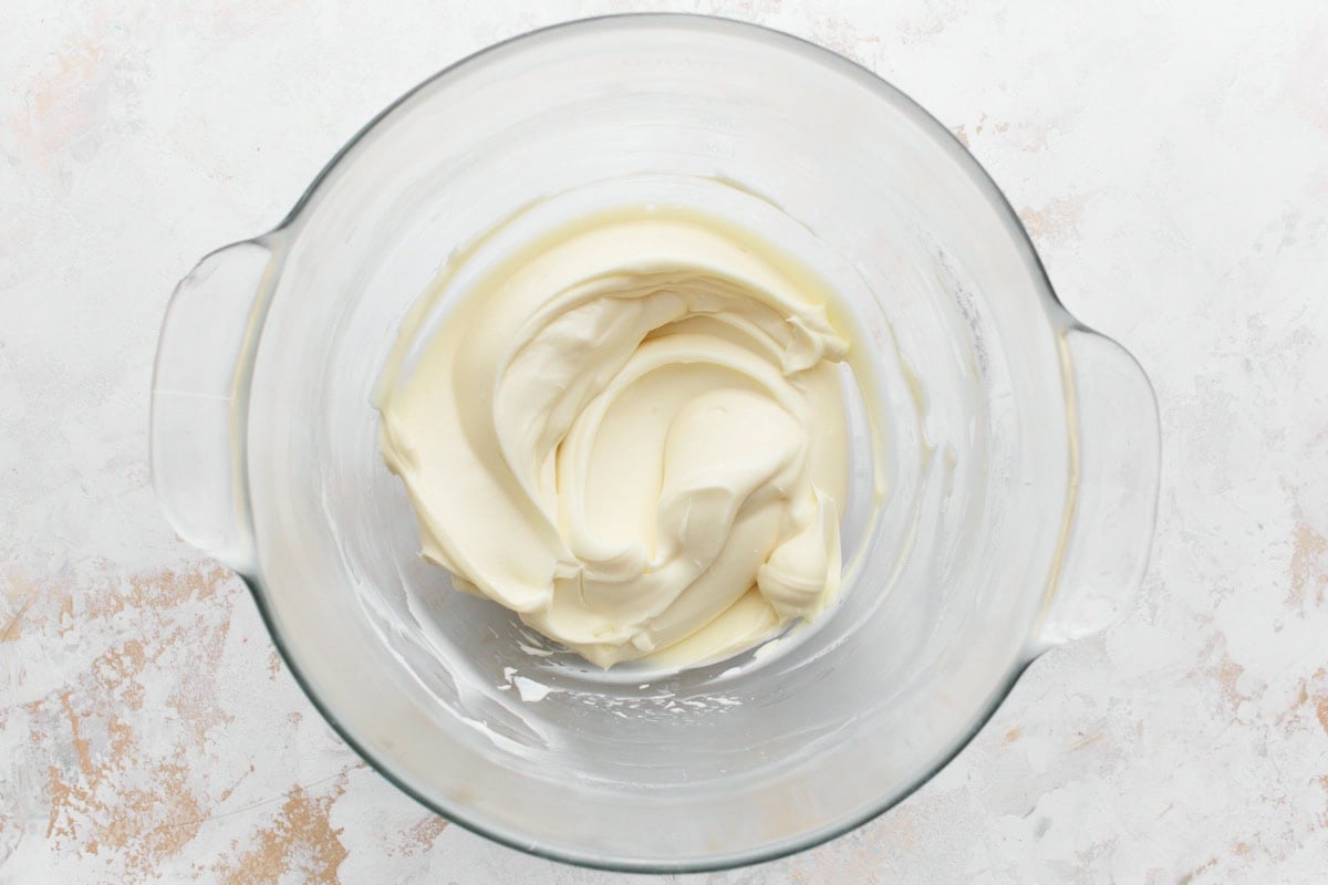 Vanilla cream cheese frosting creamed together in glass mixing bowl, with a velvety smooth texture