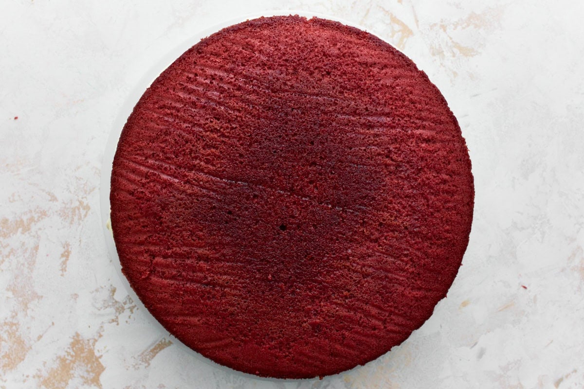 Baked gluten-free red velvet cake on a white cake plate layered 