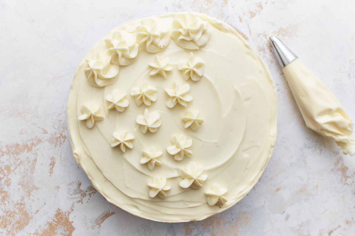 A gluten-free red velvet cake with cream cheese frosting and piped flower decorations