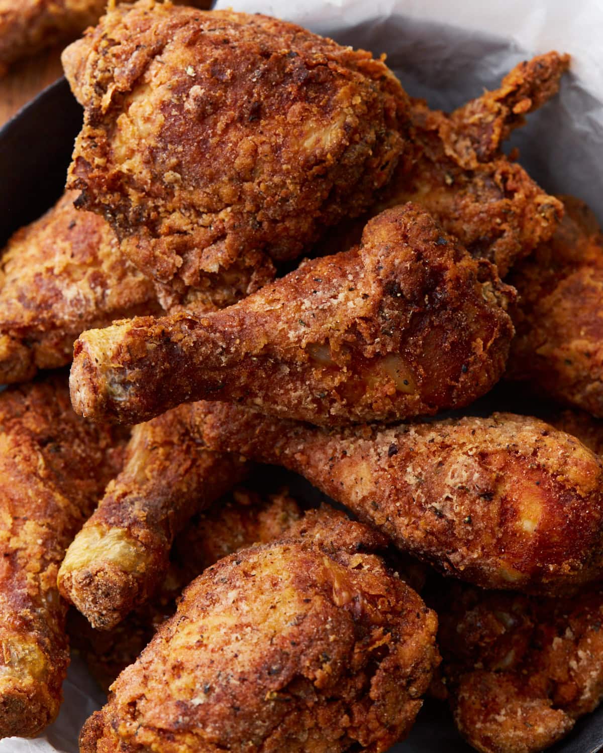Close-up of crispy, golden-brown Southern-style gluten-free fried chicken drumsticks and thighs, piled together and showcasing the crunchy texture of the seasoned batter. 