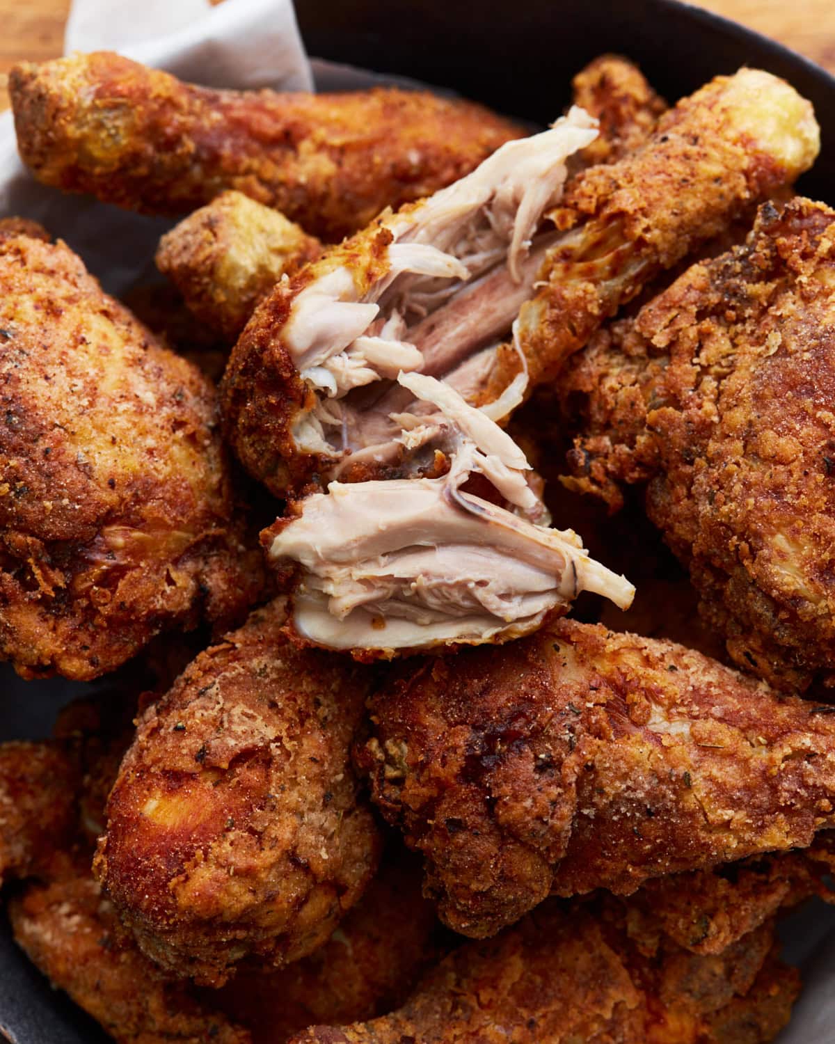 Close-up of gluten-free Southern-style fried chicken with one drumstick broken open to reveal the tender, juicy interior. 