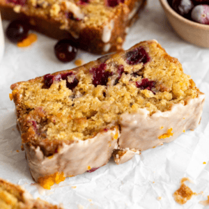 a close up of a slice of gluten-free cranberry bread with an orange glaze