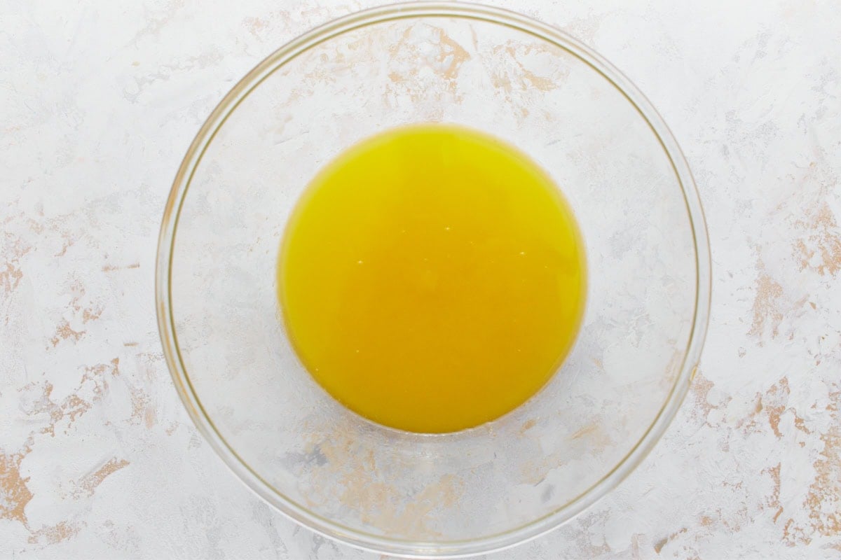 Melted butter and sugar mixture in a glass mixing bowl resting on a light surface