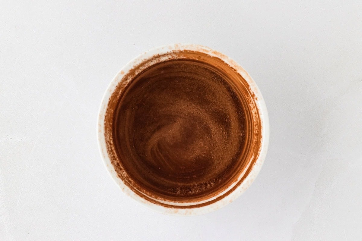 A small white ramekin dusted with cocoa powder.